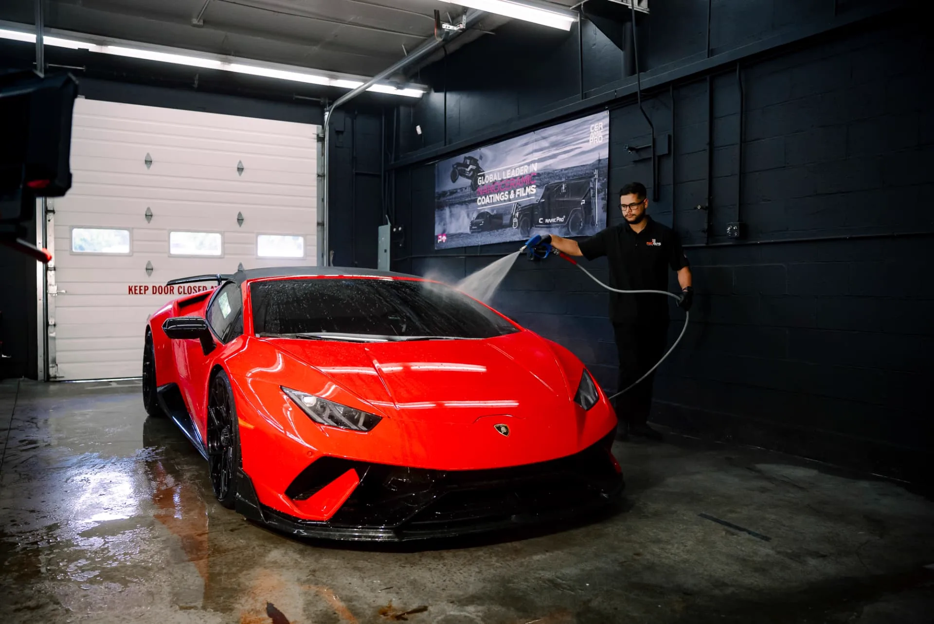 PROGUYS technician washing a red Lamborghini in the workshop